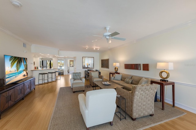 living room with ceiling fan, ornamental molding, and light hardwood / wood-style floors