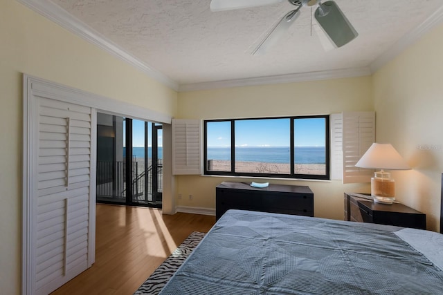 bedroom featuring a textured ceiling, ceiling fan, ornamental molding, and a water view