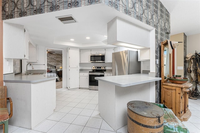 kitchen with sink, kitchen peninsula, white cabinets, and appliances with stainless steel finishes