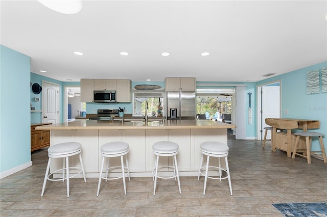 kitchen with appliances with stainless steel finishes, a breakfast bar, sink, and a kitchen island with sink