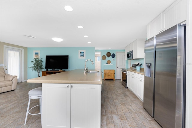 kitchen featuring stainless steel appliances, sink, a center island with sink, and white cabinets