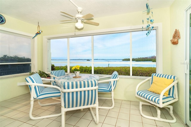 sunroom / solarium with ceiling fan and a water view