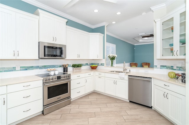 kitchen featuring sink, white cabinetry, ornamental molding, stainless steel appliances, and backsplash