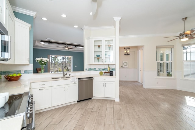 kitchen with stainless steel appliances, white cabinetry, sink, and light wood-type flooring