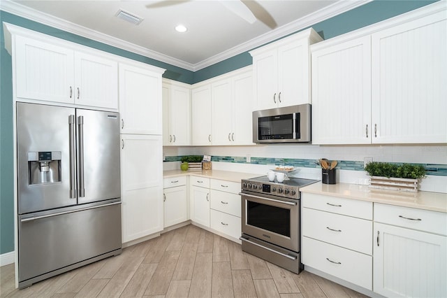 kitchen featuring ornamental molding, stainless steel appliances, light hardwood / wood-style floors, decorative backsplash, and white cabinets