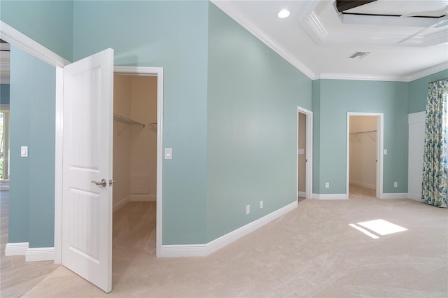 unfurnished bedroom with a towering ceiling, ornamental molding, a spacious closet, light colored carpet, and a closet