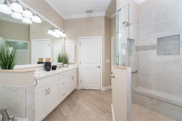 bathroom featuring hardwood / wood-style flooring, crown molding, a tile shower, and vanity