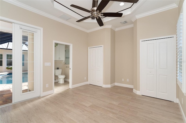 unfurnished bedroom with crown molding, two closets, light hardwood / wood-style floors, and ensuite bathroom