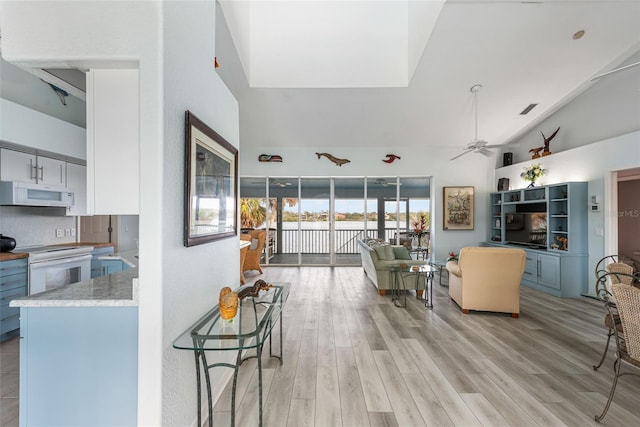 living room with lofted ceiling, light hardwood / wood-style floors, and ceiling fan