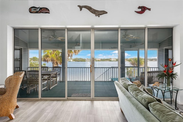 sunroom / solarium with ceiling fan, a water view, and a wealth of natural light