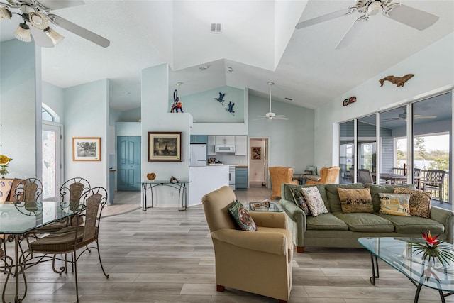 living room with a wealth of natural light, light hardwood / wood-style floors, and high vaulted ceiling