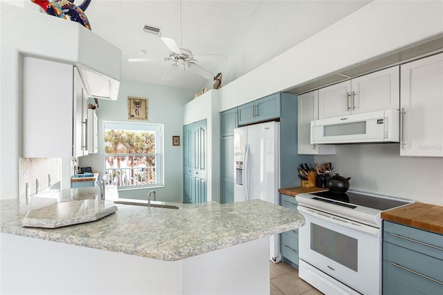 kitchen featuring white appliances, white cabinetry, blue cabinetry, kitchen peninsula, and light tile patterned floors