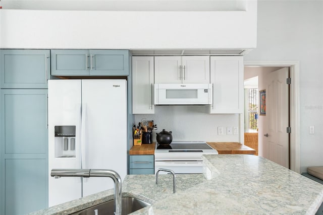 kitchen featuring light stone countertops, white appliances, and sink