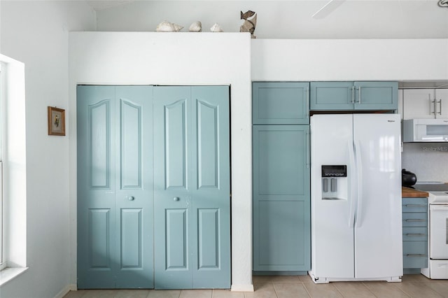 kitchen featuring light tile patterned flooring, white appliances, and wood counters