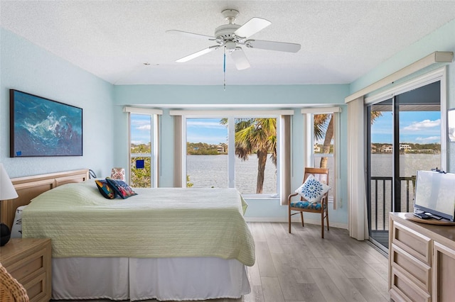 bedroom with ceiling fan, light hardwood / wood-style flooring, access to outside, and a textured ceiling