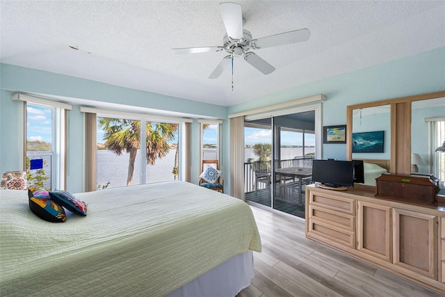 bedroom with ceiling fan, light hardwood / wood-style flooring, access to outside, and a textured ceiling