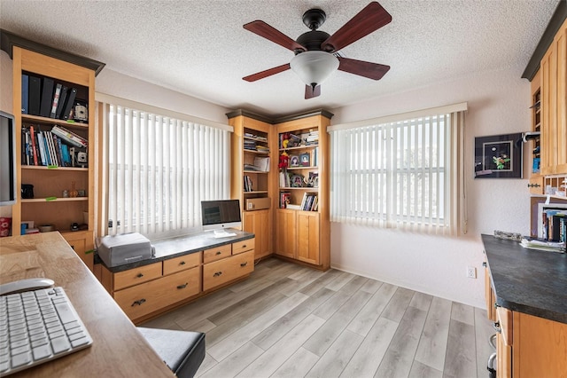 office space featuring ceiling fan, light hardwood / wood-style flooring, and a textured ceiling