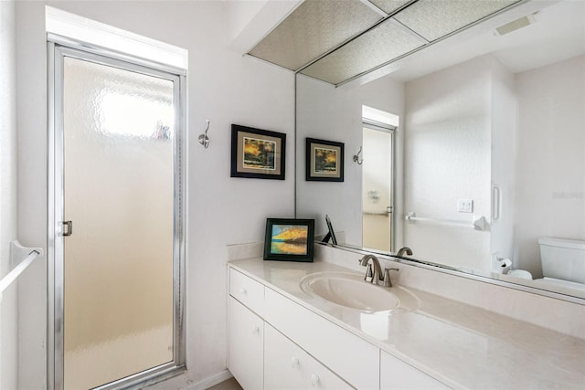 bathroom featuring a shower with door, toilet, and vanity