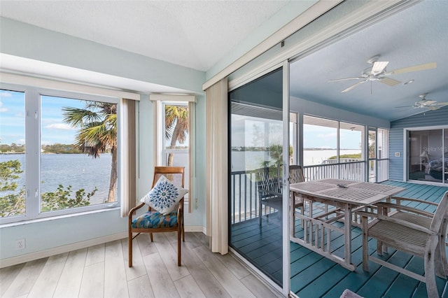 sunroom / solarium with a water view, vaulted ceiling, and ceiling fan