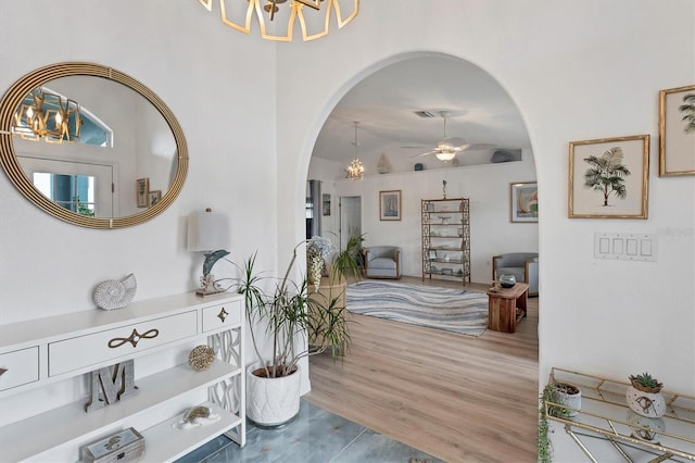 interior space with lofted ceiling, ceiling fan with notable chandelier, and wood-type flooring