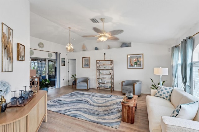 living room with ceiling fan with notable chandelier, vaulted ceiling, and light wood-type flooring