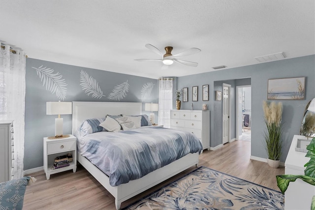 bedroom featuring ceiling fan, light hardwood / wood-style floors, and a textured ceiling