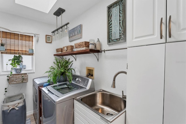 laundry area featuring sink, washer and clothes dryer, cabinets, and a skylight