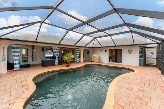 view of pool with french doors, a lanai, and a patio area