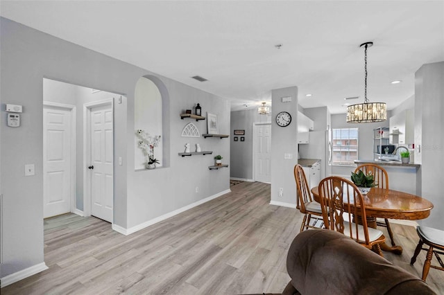 dining space featuring a notable chandelier and light wood-type flooring