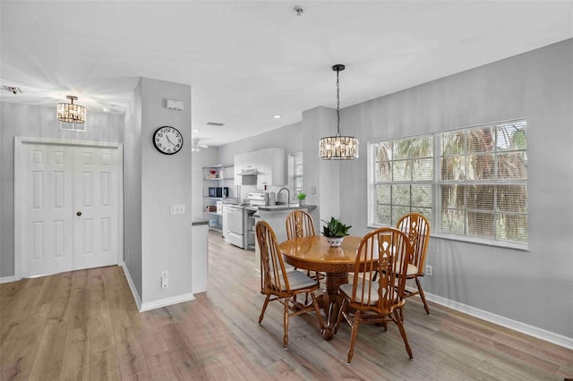 dining room with light wood-type flooring, a chandelier, and sink