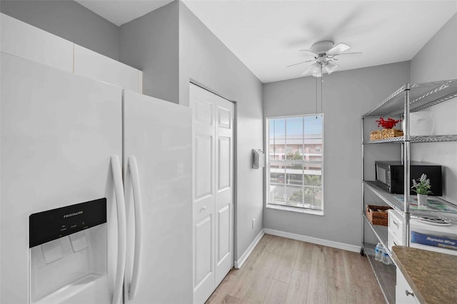 kitchen with white cabinets, light wood-type flooring, white refrigerator with ice dispenser, and ceiling fan