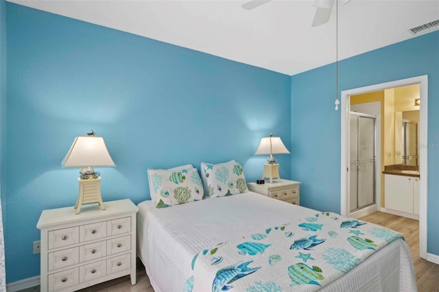 bedroom featuring ceiling fan, light hardwood / wood-style flooring, and ensuite bath