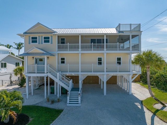 beach home with a balcony, a carport, ceiling fan, and covered porch