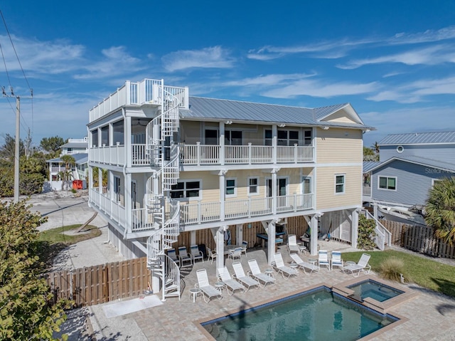 back of house with a balcony, a pool with hot tub, and a patio