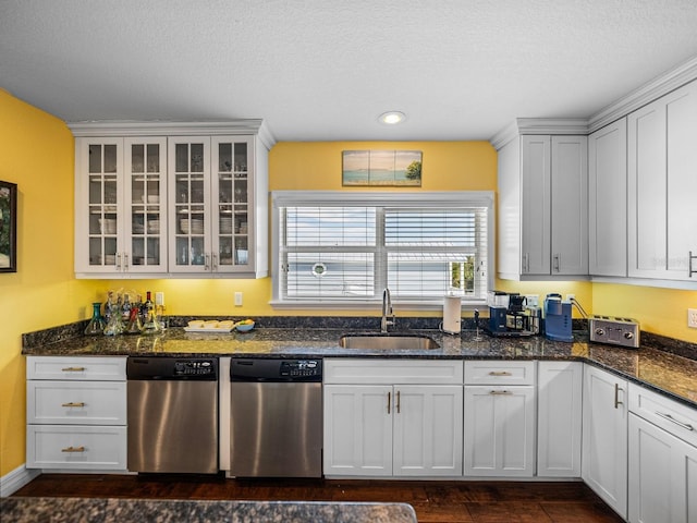 kitchen with white cabinetry, sink, stainless steel dishwasher, and dark stone countertops