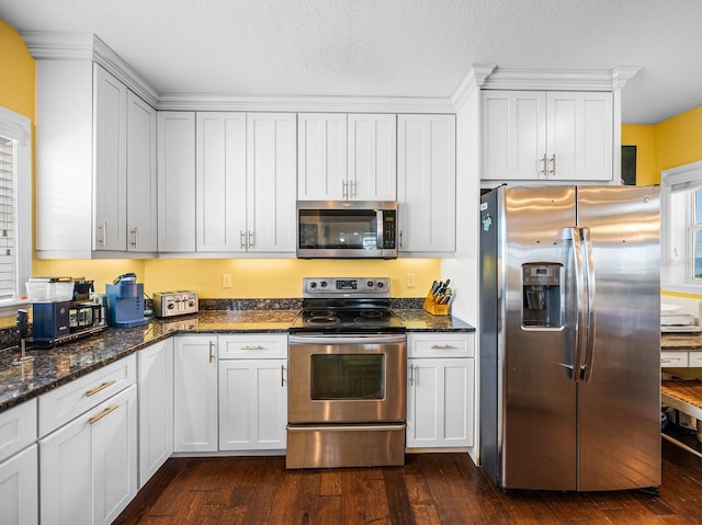 kitchen featuring white cabinetry, appliances with stainless steel finishes, dark hardwood / wood-style flooring, and dark stone countertops