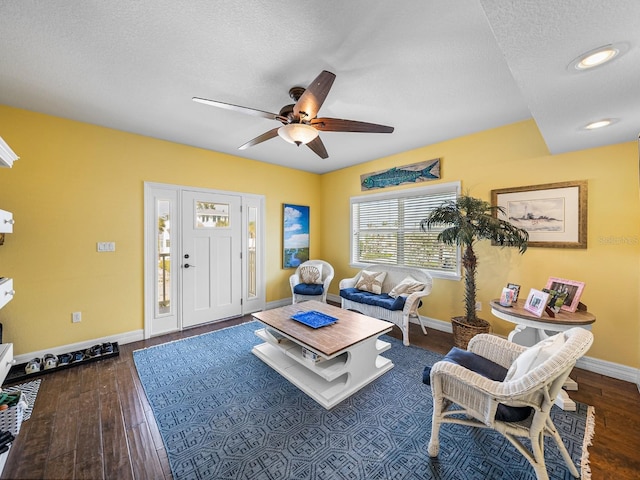 living room featuring ceiling fan, dark wood-type flooring, and a textured ceiling