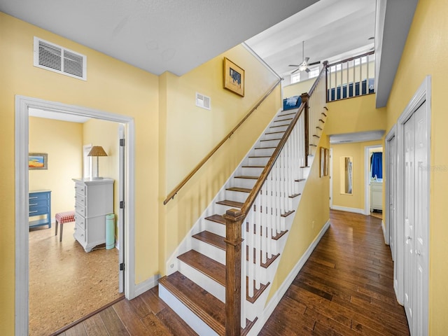 stairs with hardwood / wood-style floors, ceiling fan, and a high ceiling