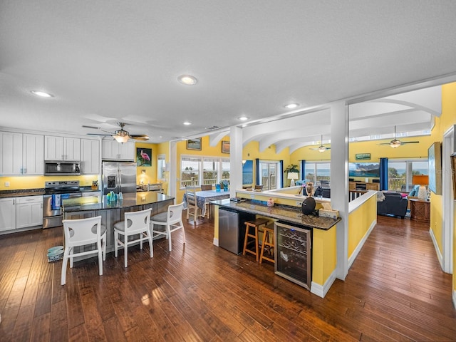 kitchen featuring a breakfast bar area, appliances with stainless steel finishes, white cabinetry, a center island, and wine cooler