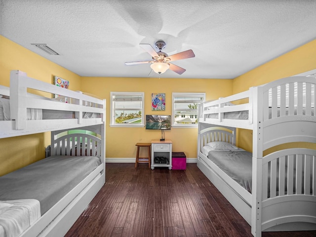 bedroom featuring dark wood-type flooring, ceiling fan, and a textured ceiling