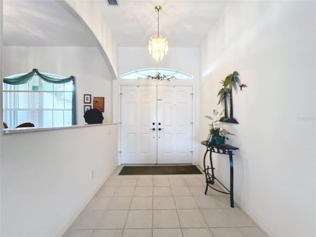 foyer featuring light tile patterned floors, plenty of natural light, and an inviting chandelier