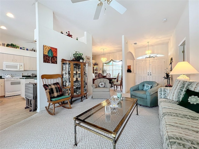 living room with light wood-type flooring and ceiling fan with notable chandelier