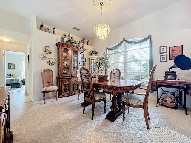 dining space featuring baseboards, light colored carpet, visible vents, and a chandelier