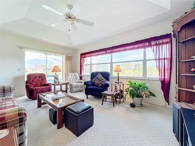 carpeted living room with ceiling fan, a wealth of natural light, a tray ceiling, and lofted ceiling