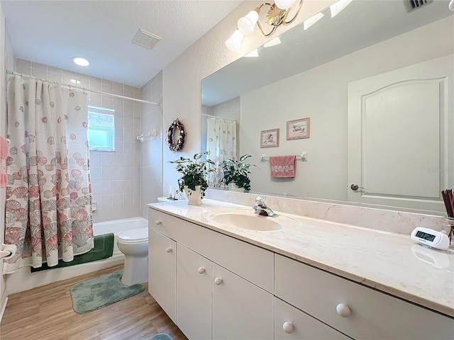 full bathroom featuring toilet, a textured ceiling, wood-type flooring, shower / bath combination with curtain, and vanity