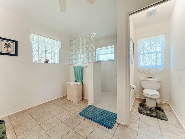 bathroom with toilet, ceiling fan, tiled shower, and tile patterned flooring