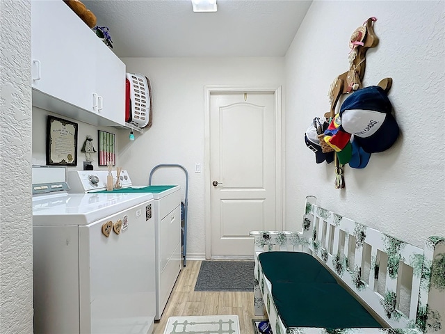 laundry room featuring washing machine and dryer, light hardwood / wood-style floors, and cabinets