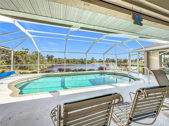 view of pool featuring a patio, glass enclosure, and a water view