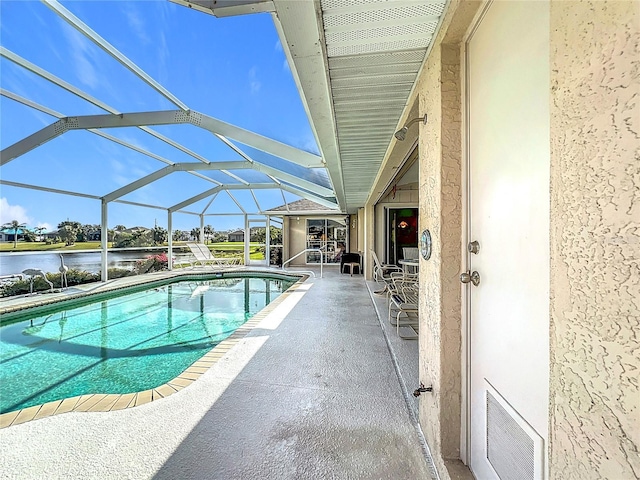 view of pool featuring a patio, a water view, and glass enclosure