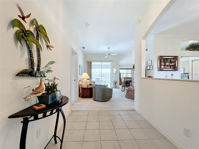 corridor featuring light tile patterned floors, light colored carpet, and baseboards